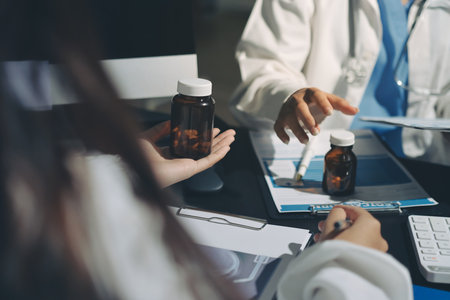 Two doctors and a female nurse meet at a table in the hospital, collaborating on medical tasks using laptops and computersの写真素材