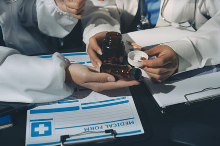 Two doctors and a female nurse meet at a table in the hospital, collaborating on medical tasks using laptops and computersの写真素材