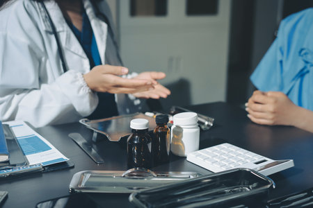 Female doctor holding a medicine bottle is checking the quality of medicine and recording patient information at the hospital. Medical and health care concept.の写真素材