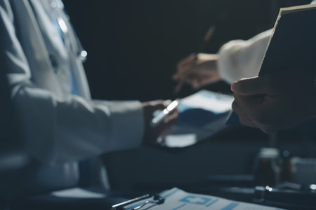 Two doctors and a female nurse meet at a table in the hospital, collaborating on medical tasks using laptops and computersの写真素材