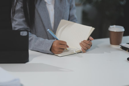 Asian Businesswoman Using laptop computer and working at office with calculator document on desk, doing planning analyzing the financial report, business plan investment, finance analysis concept.の写真素材