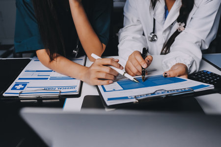 Group of doctors attending seminar in hospital lecture hall with senior physician giving medical presentation and professional training session on healthcare practicesの写真素材