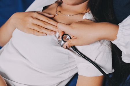 Doctor examining patient with stethoscope in hospital bed. Medical care and healthcare concept in a clinical setting.の写真素材