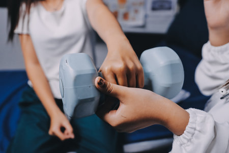 old woman training with physiotherapist using dumbbells at home therapist assisting senior woman with exercises in nursing home elderly patient using dumbbells with outstretched arms no logos no branの写真素材