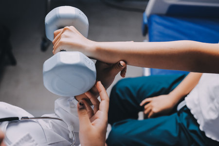 old woman training with physiotherapist using dumbbells at home therapist assisting senior woman with exercises in nursing home elderly patient using dumbbells with outstretched arms no logos no branの写真素材