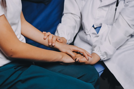 Doctor giving hope. Close up shot of young female physician leaning forward to smiling elderly lady patient holding her hand in palms. Woman caretaker in white coat supporting encouraging old personの写真素材