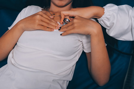 Doctor examining patient with stethoscope in hospital bed. Medical care and healthcare concept in a clinical setting.の写真素材