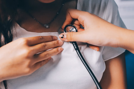 Doctor examining patient with stethoscope in hospital bed. Medical care and healthcare concept in a clinical setting.の写真素材
