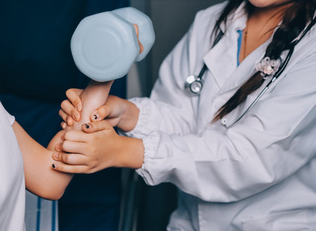 old woman training with physiotherapist using dumbbells at home therapist assisting senior woman with exercises in nursing home elderly patient using dumbbells with outstretched arms no logos no branの写真素材