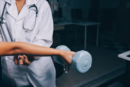 old woman training with physiotherapist using dumbbells at home therapist assisting senior woman with exercises in nursing home elderly patient using dumbbells with outstretched arms no logos no branの写真素材