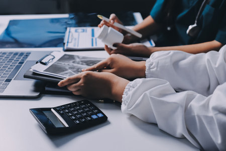 Group of doctors attending seminar in hospital lecture hall with senior physician giving medical presentation and professional training session on healthcare practicesの写真素材