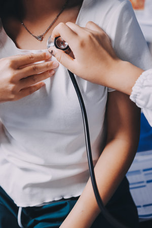 Doctor examining patient with stethoscope in hospital bed. Medical care and healthcare concept in a clinical setting.の写真素材