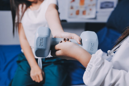 old woman training with physiotherapist using dumbbells at home therapist assisting senior woman...