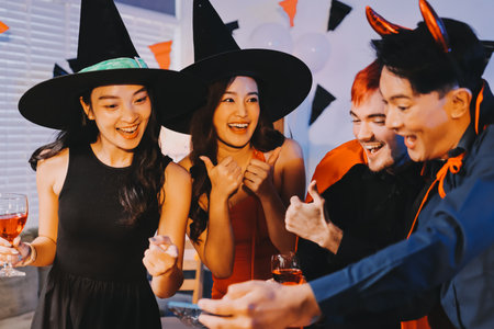 Joyful Halloween party with coworkers in costumes, celebrating with drinks and laughter, fostering teamwork and festive spiritの写真素材