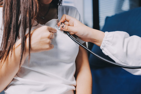 Doctor examining patient with stethoscope in hospital bed. Medical care and healthcare concept in a clinical setting.の写真素材
