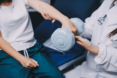 old woman training with physiotherapist using dumbbells at home therapist assisting senior woman with exercises in nursing home elderly patient using dumbbells with outstretched armsの写真素材