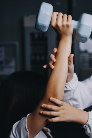 old woman training with physiotherapist using dumbbells at home therapist assisting senior woman with exercises in nursing home elderly patient using dumbbells with outstretched arms no logos no branの写真素材
