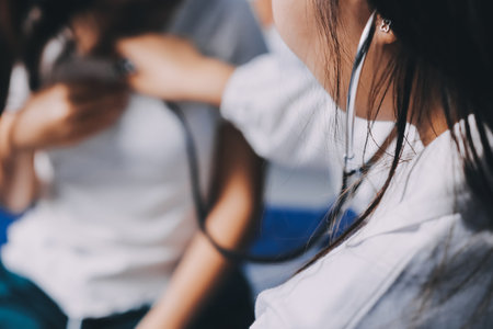 Doctor examining patient with stethoscope in hospital bed. Medical care and healthcare concept in a clinical setting.の写真素材