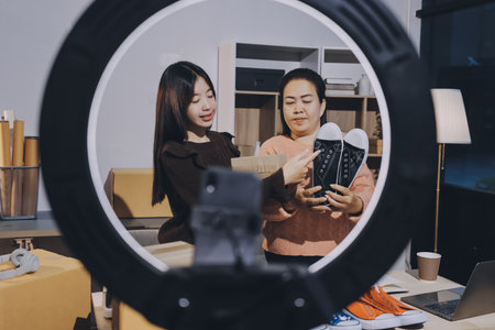 Asian woman selling clothes on camera live broadcast on social network at home, Online selling clothes on social media. Blogger woman influencer, SME retail store owner.の写真素材