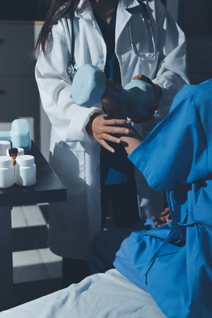 Physical therapist assisting a woman with dumbbell exerciseの写真素材