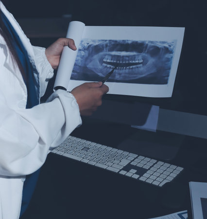 Two doctors and a female nurse meet at a table in the hospital, collaborating on medical tasks using laptops and computersの写真素材