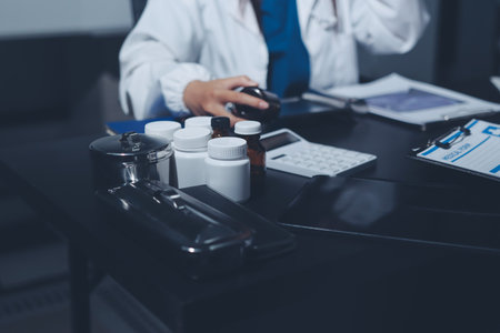 Two doctors and a female nurse meet at a table in the hospital, collaborating on medical tasks using laptops and computersの写真素材