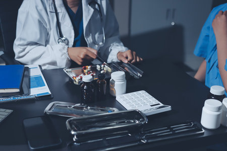 Female doctor holding a medicine bottle is checking the quality of medicine for any side effects the patient or not and recording patient information at the hospital. medical and health care conceptの写真素材