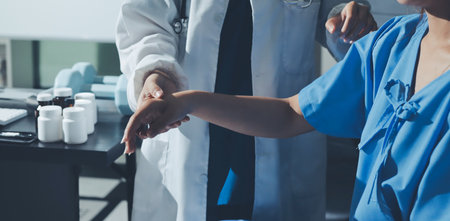 Doctor examining patient's elbow in hospital room