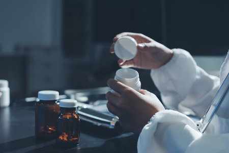 Female doctor holding a medicine bottle is checking the quality of medicine for any side effects the patient or not and recording patient information at the hospital. medical and health care conceptの写真素材