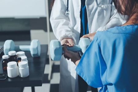 Physical therapist assisting a woman with dumbbell exerciseの写真素材