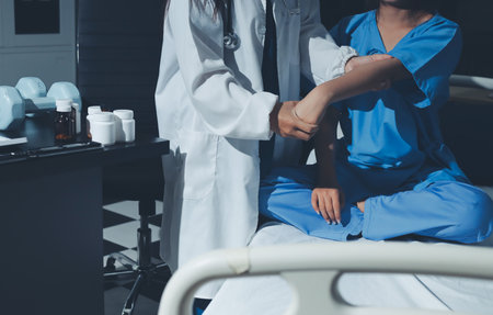 Doctor examining patient's elbow in hospital roomの写真素材