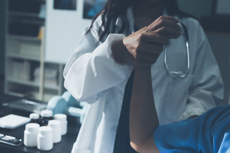 Doctor examining patient's elbow in hospital roomの写真素材