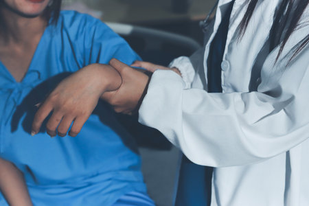 Doctor examining patient's elbow in hospital roomの写真素材