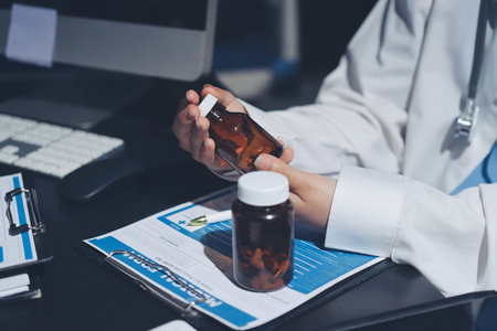 Two doctors and a female nurse meet at a table, collaborating on medical tasks using laptops and computersの写真素材
