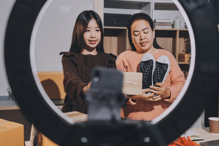 Asian woman selling clothes on camera live broadcast on social network at home. Online selling clothes on social media. Blogger woman influencer, SME retail store owner.の写真素材