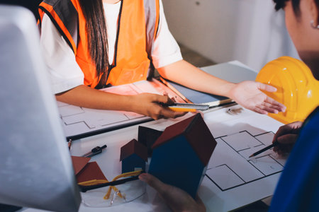 Closeup of team of engineers meeting analyze blueprints consult project on table in manufacturing factory. Working in manufacturing plant or production plant.の写真素材