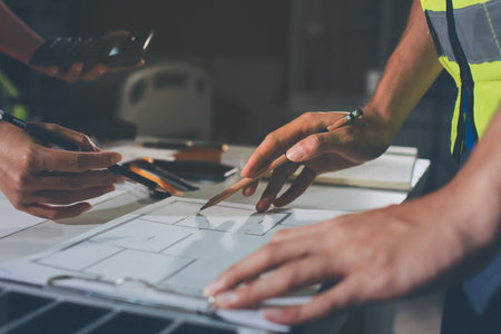 Closeup of team of industrial engineers meeting analyze machinery blueprints consult project on table in manufacturing factory. Working in manufacturing plant or production plant.の写真素材