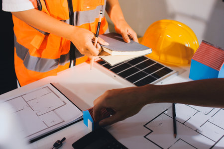 Closeup of team of industrial engineers meeting analyze machinery blueprints consult project on table in manufacturing factory. Working in manufacturing plant or production plant.の写真素材