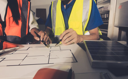 Closeup of team of industrial engineers meeting analyze machinery blueprints consult project on table in manufacturing factory. Working in manufacturing plant or production plant.の写真素材