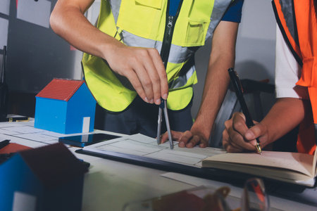 Closeup of team of industrial engineers meeting analyze machinery blueprints consult project on...