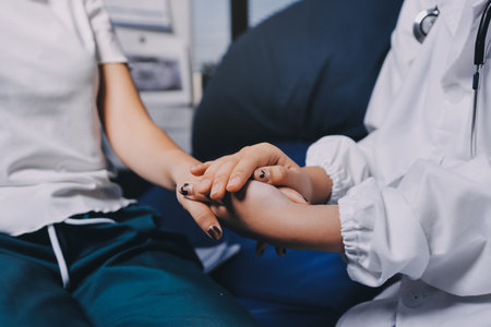 Doctor giving hope. Close up shot of young female physician leaning forward to smiling elderly lady patient holding her hand in palms. Woman caretaker in white coat supporting encouraging old personの写真素材