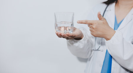Portrait of Asian doctor woman standing holding coffee cup in white studio backgroundの写真素材