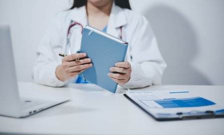 Middle aged female doctor working on laptop in doctor's room