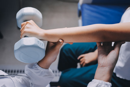 old woman training with physiotherapist using dumbbells at home therapist assisting senior woman...