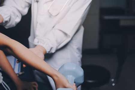 old woman training with physiotherapist using dumbbells at home therapist assisting senior woman with exercises in nursing home elderly patient using dumbbells with outstretched arms no logos no branの写真素材