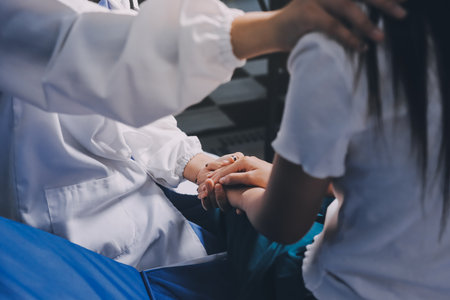 Doctor giving hope. Close up shot of young female physician leaning forward to smiling elderly lady patient holding her hand in palms. Woman caretaker in white coat supporting encouraging old personの写真素材
