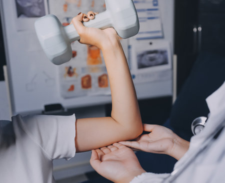 old woman training with physiotherapist using dumbbells at home therapist assisting senior woman with exercises in nursing home elderly patient using dumbbells with outstretched arms no logosの写真素材
