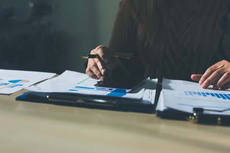 Close-up of businessman's hands making notes, smartphone, chart, desk, officeの写真素材