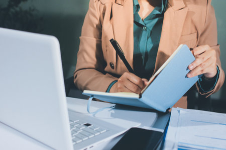 Close-up of businessman's hands making notes, mobiles, chart, desk, officeの写真素材