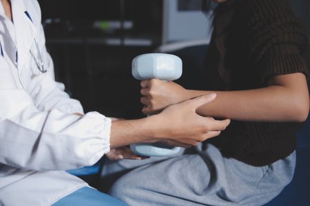 Old woman training with physiotherapist using dumbbells at home. Therapist assisting senior woman with exercises in nursing home. Elderly patient using dumbbells with outstretched arms.の写真素材